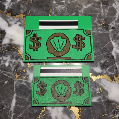 Two green card cleeves with a retro money design, displayed side-by-side against a marble background.
